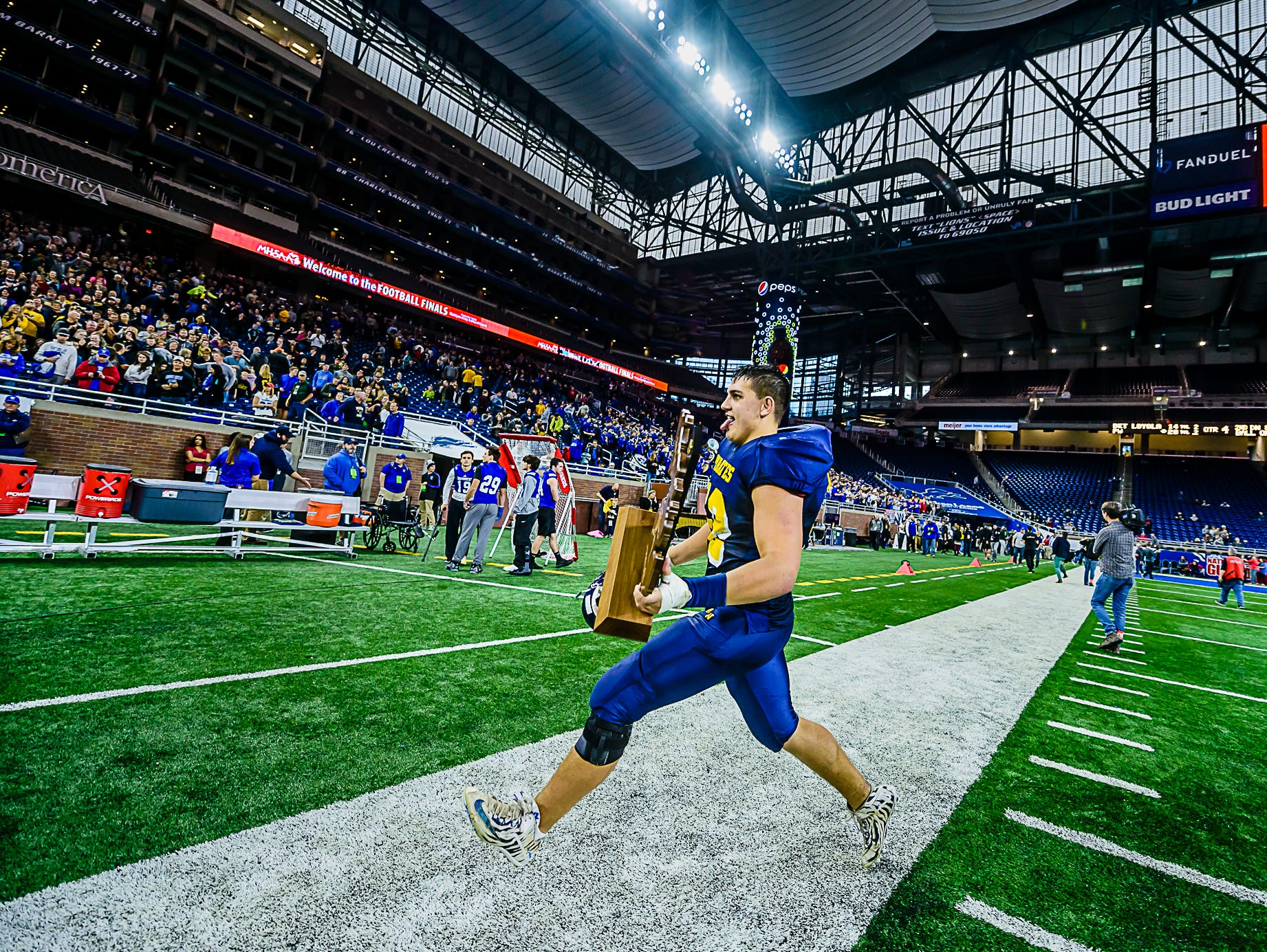 Pewamo-Westphalia senior offensive lineman prances toward the Pewamo-Westphalia stands carrying the Pirates Division 7 state championship trophy Saturday November 26, 2016 at Ford Field in Detroit.