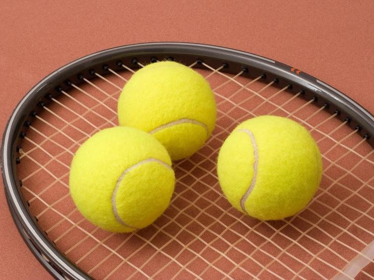 Three tennis balls on a racket head