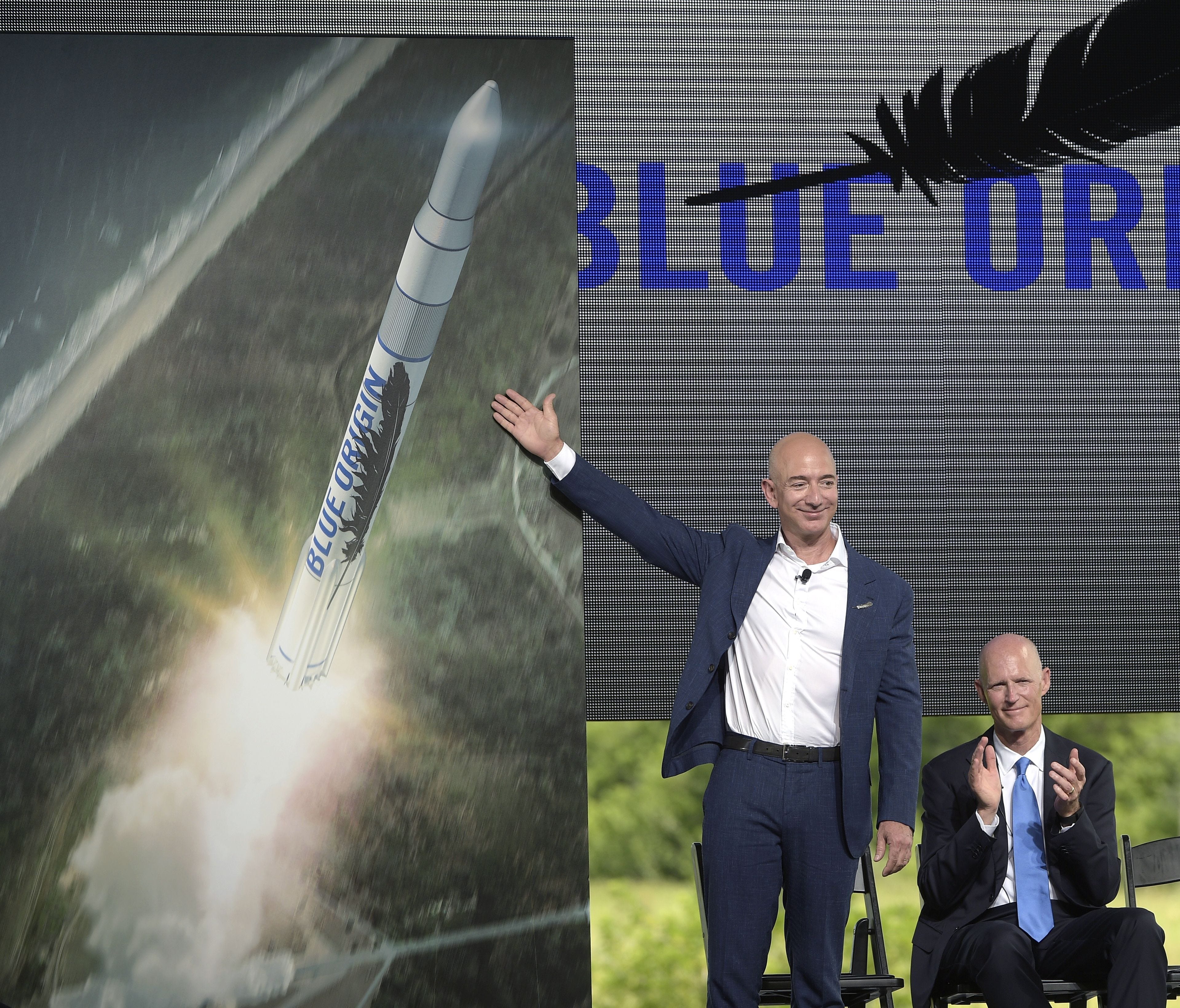 Amazon CEO Jeff Bezos, left, unveils the new Blue Origin rocket, as Florida Gov. Rick Scott applauds, during a news conference at the Cape Canaveral Air Force Station in Cape Canaveral, Fla., in September