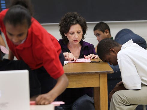Reading teacher Lorie Shively helps a student on March 2, 2012, at Emma Donnan Middle School in Indianapolis. Indianapolis Public Schools have the fewest number of absences per teacher and the fewest percentage of teachers who were absent more than 1