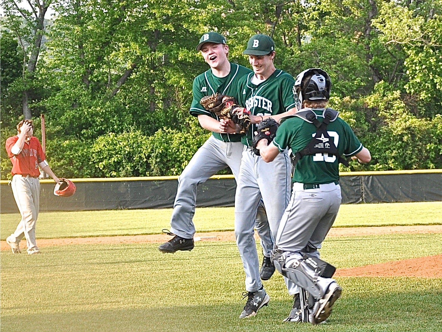 Third baseman Ryan Wynne and catcher Tim Holler mob Devin O'Connor after his complete-game, shutout win over Tappan Zee in the Class A seminfinals.