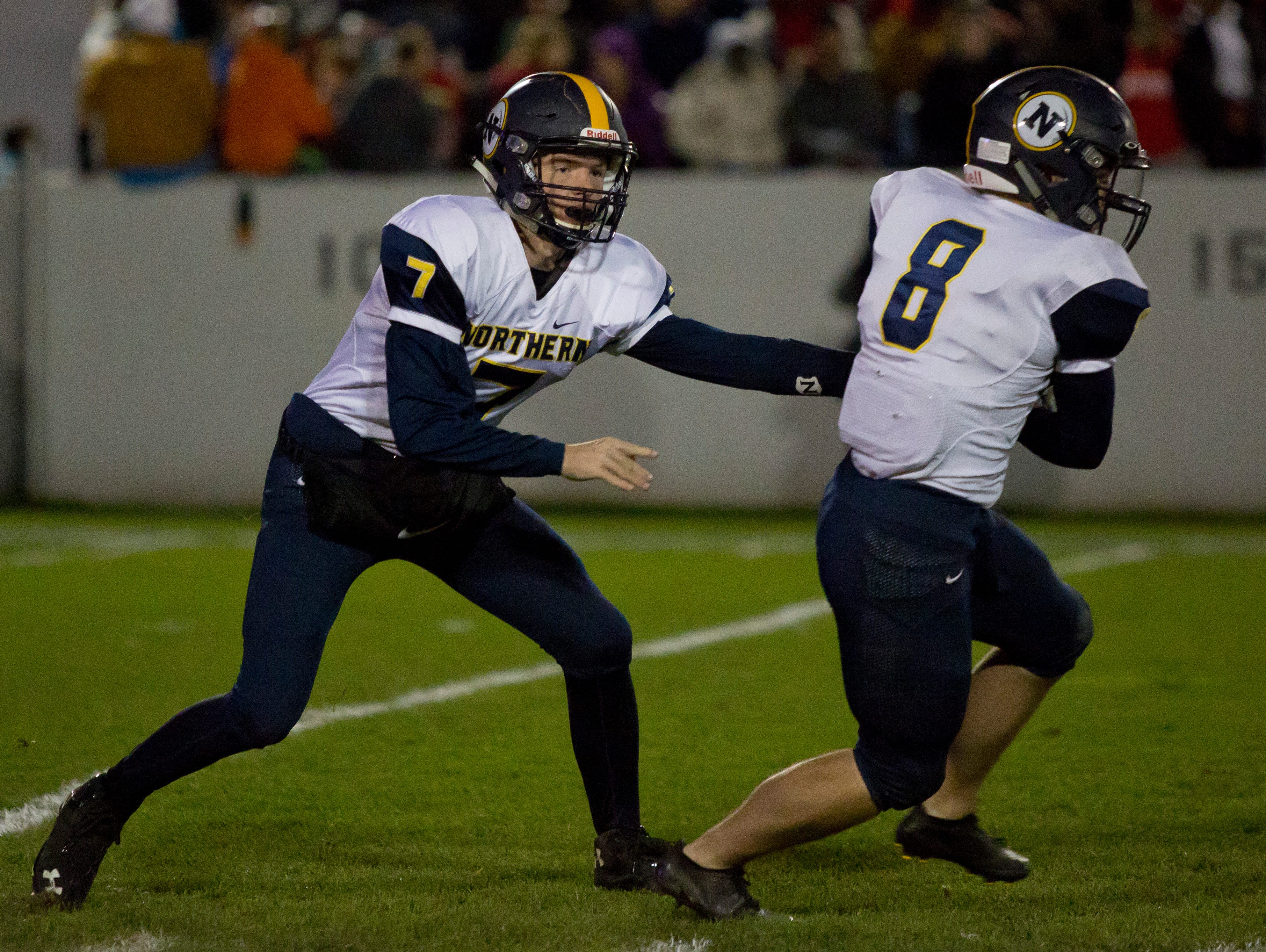 Port Huron Northern junior Billy Fealko hands off the ball to junior Travis Hughes during the Crosstown Showdown Friday, October 23, 2015 at Memorial Stadium in Port Huron.