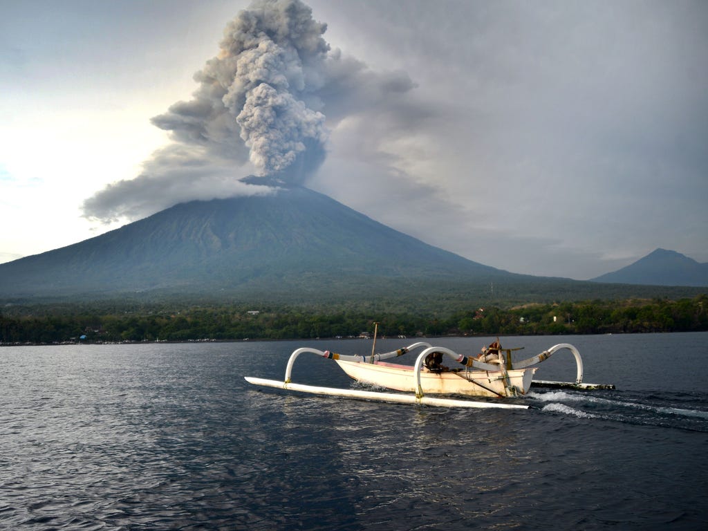 A fisherman drives a traditional boat as Mount Agung erupts  on Indonesia's resort island of Bali on Nov. 28, 2017. Indonesian authorities extended the closure of the international airport on the resort island of Bali for a second day over fears of a