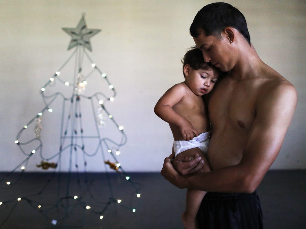 Jesus M. Montijo poses with his son Damian Kaleb, 1, in the shelter for Hurricane Maria victims where they currently reside, in front of the shelter's Christmas tree on Christmas day, Dec. 25, 2017 in Toa Baja, Puerto Rico. He said their home was des