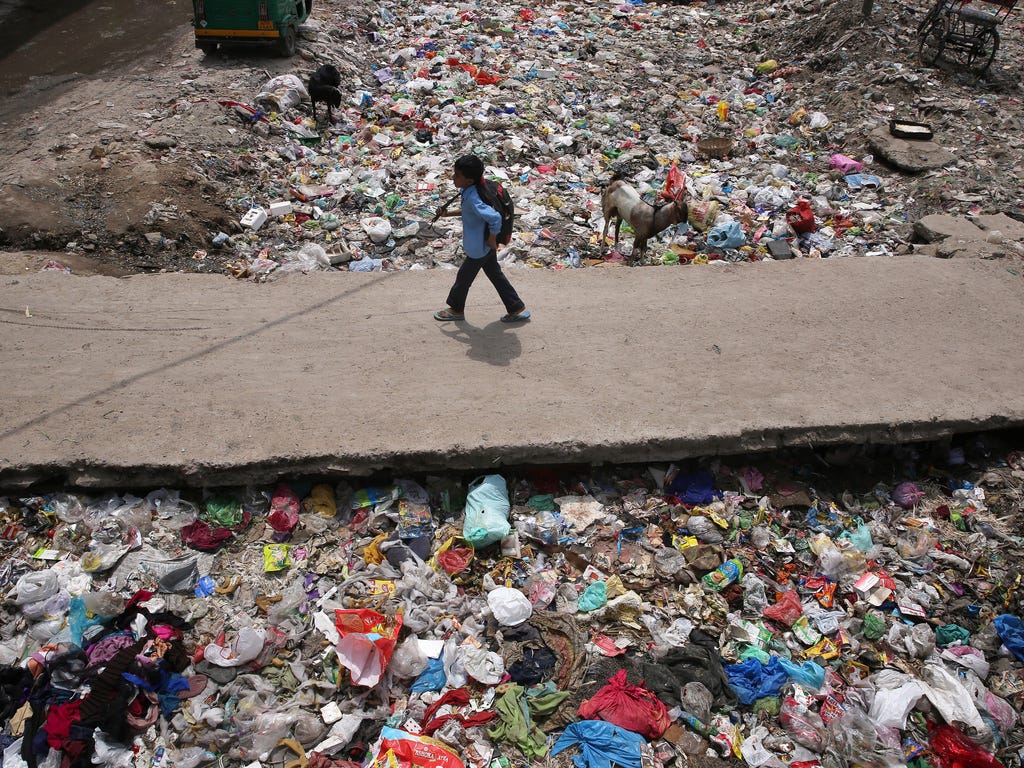 An Indian child walks near the waste dumped inside a drain on the World Earth day in New Delhi, India. Earth Day is celebrated on April 22 in many countries to inspire awareness of and appreciation for the earth's environment.