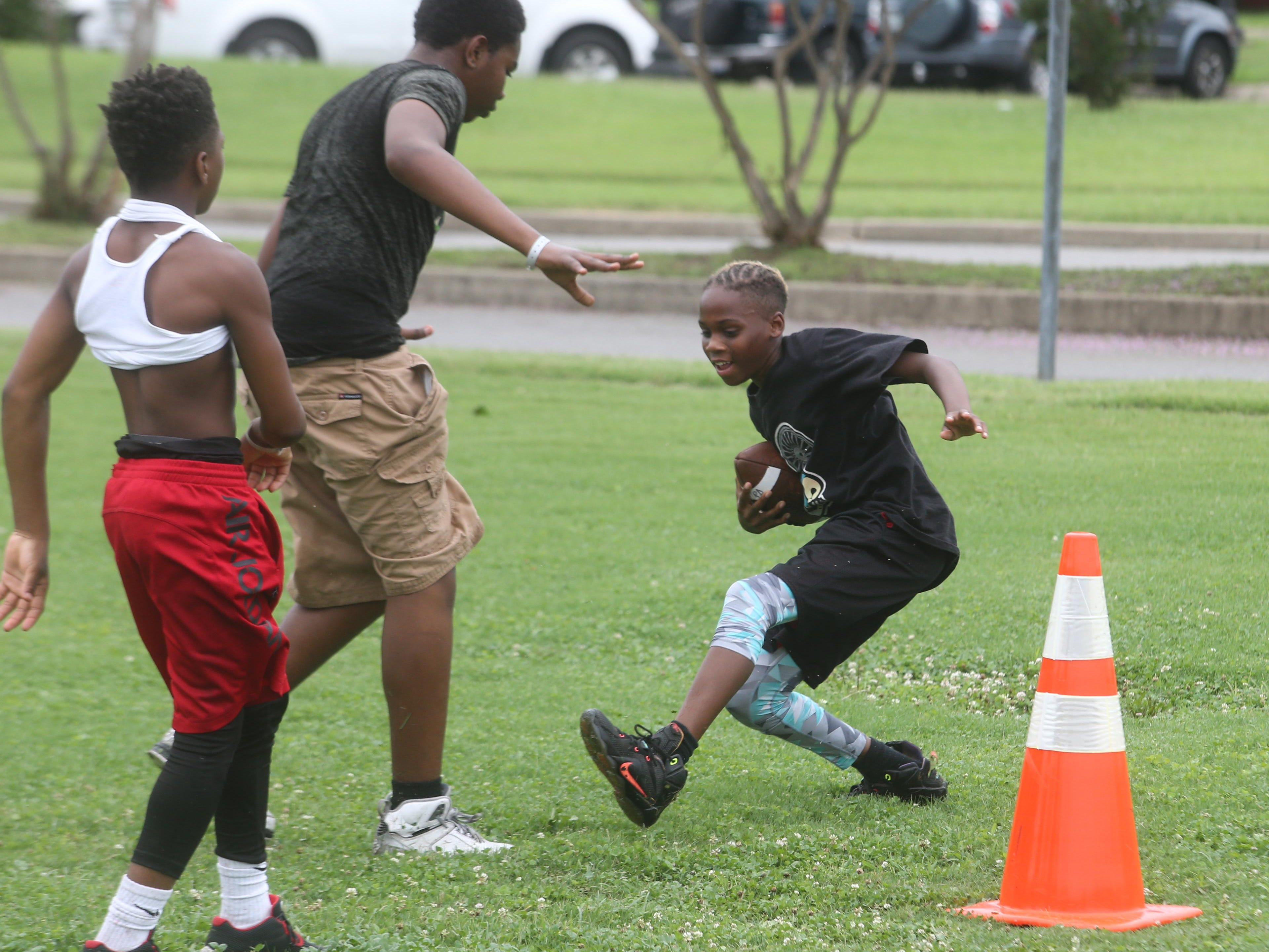 Whitworth Buchanan student Marshawn Scales, 13, tries to miss a defender while going for the end zone.