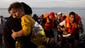Syrian refugees arrive on a dinghy after crossing from