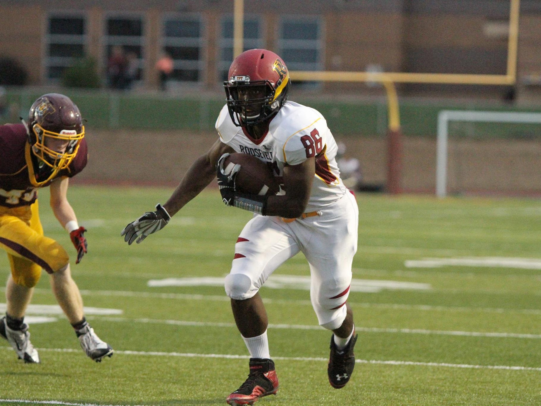 Roosevelt's DeMareio Hester moves up field after catching a pass as Harrisburg's Michael Curry pursues.