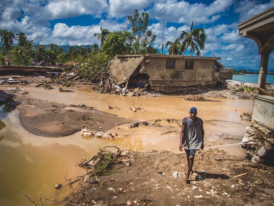 A man walks across flooded countryside in Nippes, Haiti.