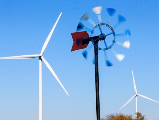 An ornamental windmill spins in front of wind turbines near Steele 