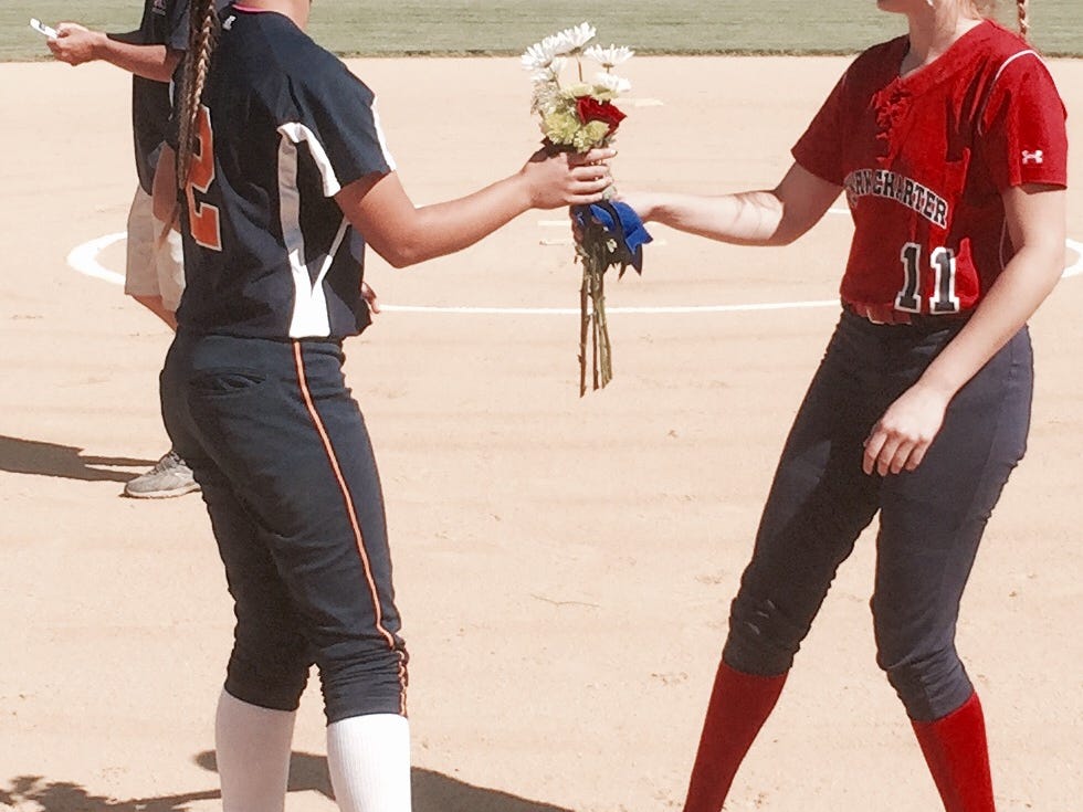 Julia Freeth, right, of Newark Charter presents flowers to Delmar’s Shelby Murphy before Thursday’s softball game at Folk Park in Newark.