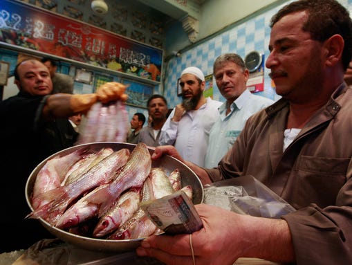 Shop owner Ehab el-Yamani, left, sells a fish dish