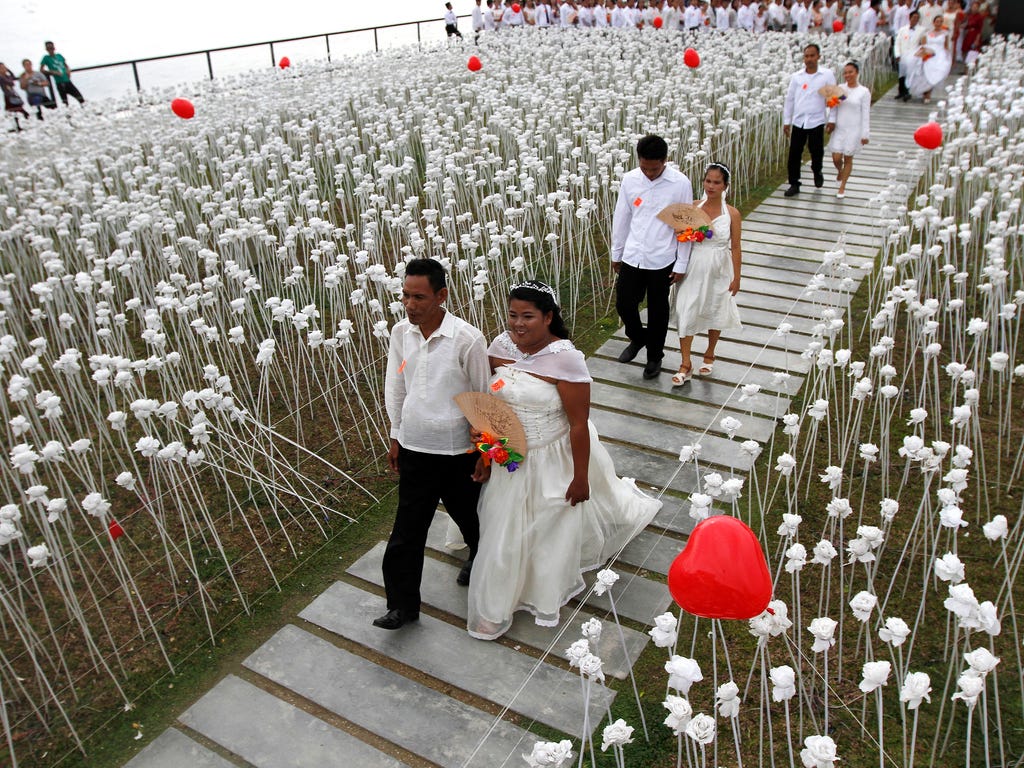 A couple walks next to flowers during a mass wedding on Valentine's Day in the town of Cordova, Cebu island, Philippines. According to news reports, thousands of couples tied the knot at mass weddings held in different parts of the country that was o