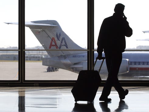 A traveler talks on his cellphone as he walks past a parked American Airlines at   O'Hare International Airport in Chicago.