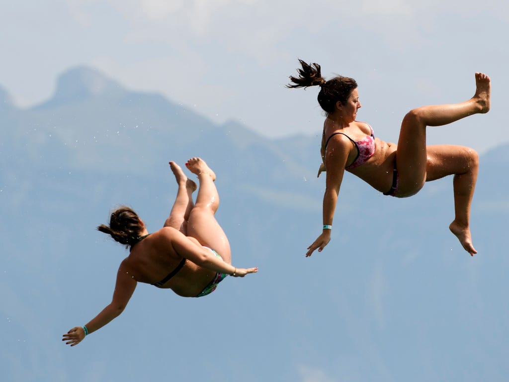 People fall into Geneva Lake after sliding down a 15 meter high water slide in front of the Swiss Alps as they enjoy the sunny and warm weather during the Summerslide Festival in Pully, Switzerland.