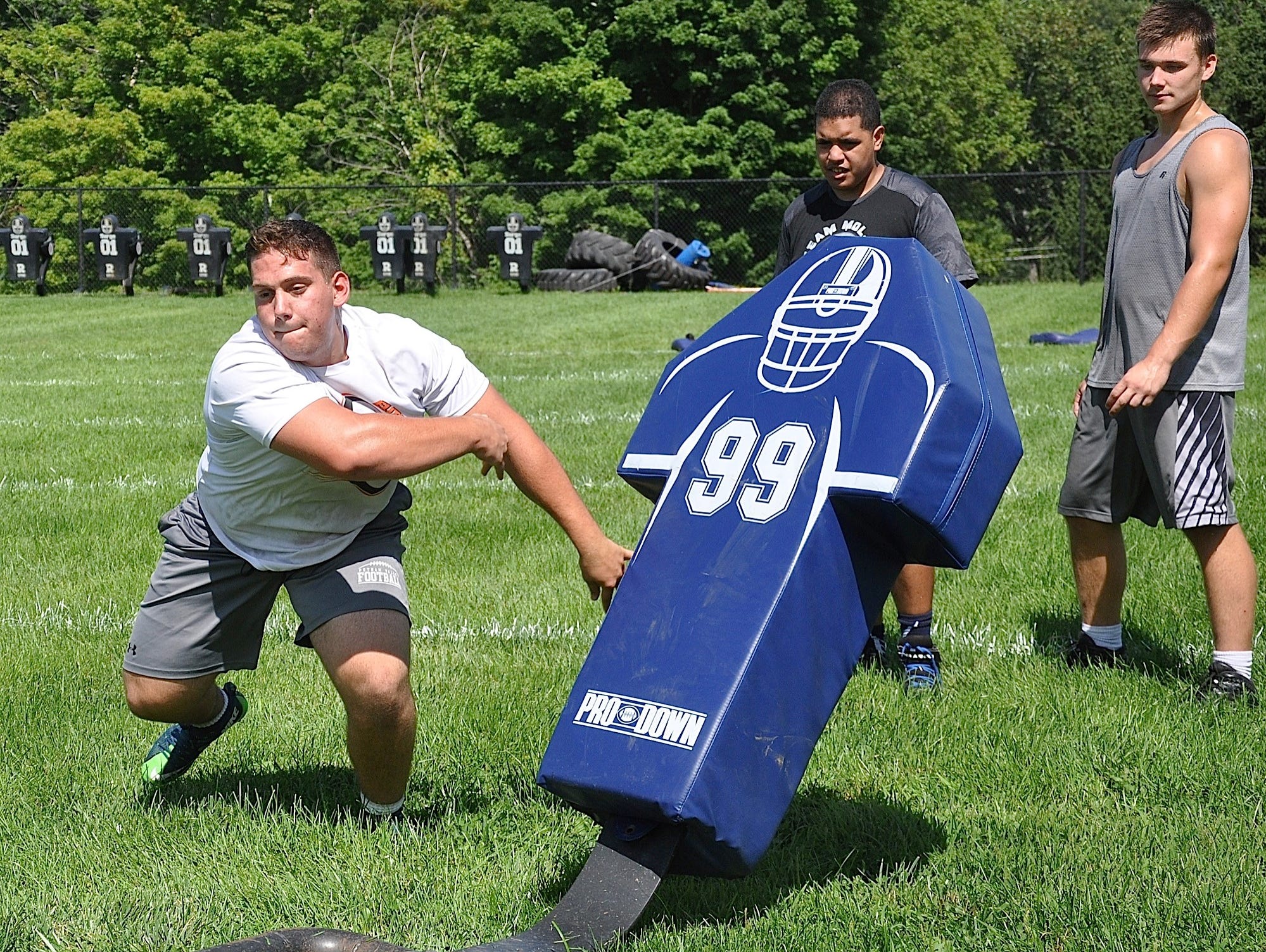 Returning All-Section lineman Constantine George pushes tackling dummy out of way during defensive rushing drill at Putnam Valley.