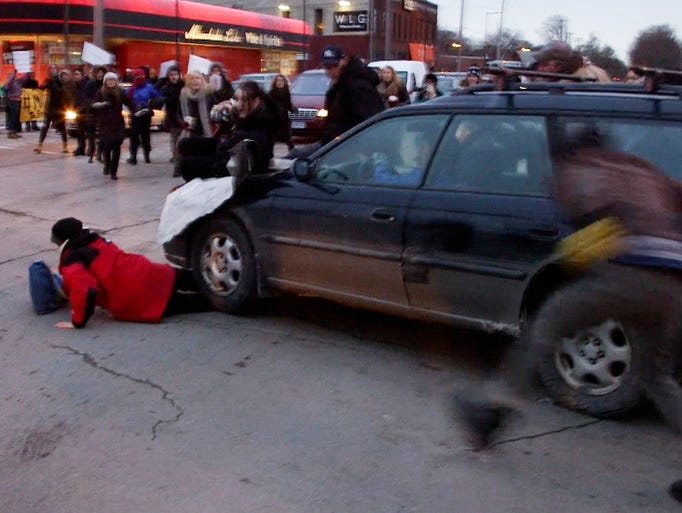 A car plows through a Ferguson rally after protesters