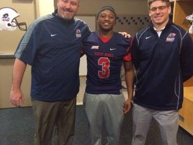 Robert Morris assistant head coach Scott Farison, left, Delano Madison and receivers coach Nick McVay smile in the locker room. Madison’s Michigan Elite 7-on-7 coach George Yarberry helped him meet with Farison.