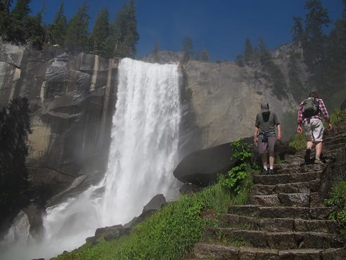 FILE - In this July 20, 2011 file photo, Hikers walk on the Mist Trail to Vernal Fall in Yosemite, Calif. Visitors to America's national parks will encounter fewer rangers, find locked restrooms and visitors centers, and see trash cans emptied less o