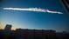 A contrail from a meteorite drifts over the city.