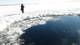 A man stands near a hole in the ice on Chebarkul Lake after a meteor strike.