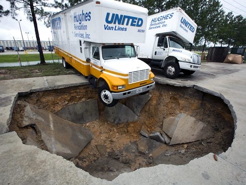 Large Sinkhole on Truck Hangs Over The Edge Of A Sinkhole That Opened Up In A Parking