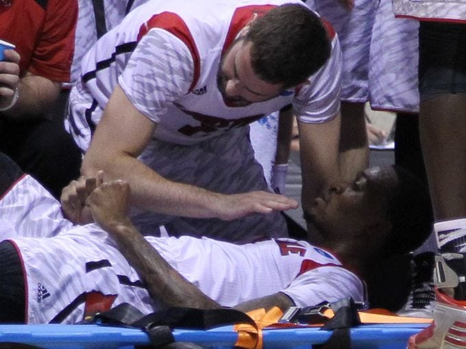 Louisville Cardinals guard/forward Luke Hancock gives encouragement to guard Kevin Ware as Ware is taken off the court on a stretcher in the first half against the Duke Blue Devils at Lucas Oil Stadium.