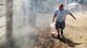 A man carries a bucket of water as he battles a brush fire on his property in Banning.