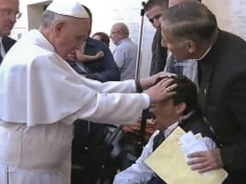 In this image made from video provided by APTN, Pope Francis lays his hands on the head of a young man on May 19 after celebrating Mass in St. Peter's Square. The young man heaved deeply a half-dozen times, convulsed and shook, and then slumped in hi