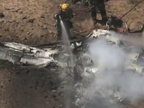 Firefighters douse wreckage from one of two single-engine planes that collided Friday, May 31, 2013, above north Phoenix.