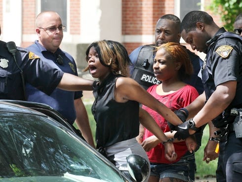 Cleveland police take a woman into custody after a fight that broke out at Michael R. White Elementary School on Friday at a kindergarten graduation ceremony.