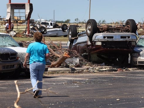 A person looks at cars damaged by a tornado in El Reno, Okla.