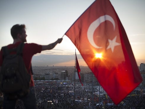 A protester waves the Turkish flag from a rooftop at Taksim Square on June 3 in Istanbul, Turkey. The protests began initially over the fate of Taksim Gezi Park, one of the last significant green spaces in the center of the city.