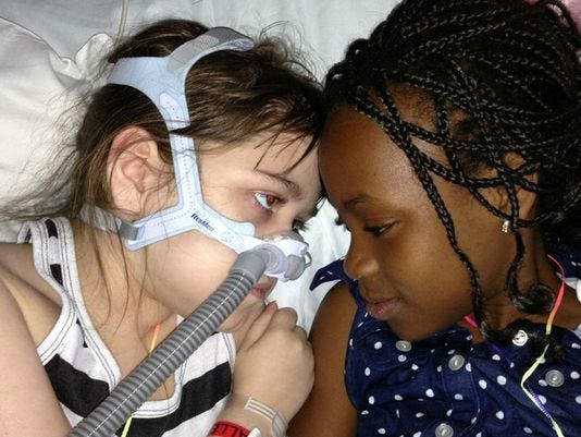 Sarah Murnaghan, left, lies in her hospital bed next to adopted sister Ella