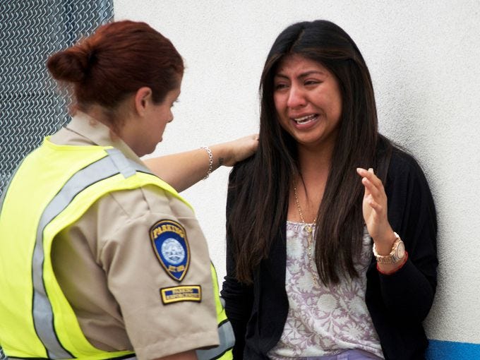 Priscilla Morales cries as she is consoled by a parking enforcement officer Friday, in Santa Monica, Calif.  Morales was in the library at Santa Monica College, where a gunman who allegedly killed at least four people with an assault-style rifle was shot to death in a gunfight with police.