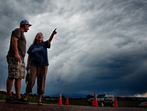 Jasen Dill, left, and Judy Pohlod discuss returning to their homes, which made it through the Black Forest fire safely, as a storm passes overhead Friday in Colorado Springs, Colo.