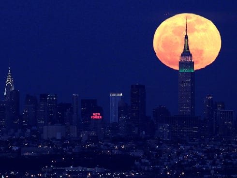 A full moon rises behind the Empire State Building in New York in April 2012. This weekend, a supermoon will rise over the USA.