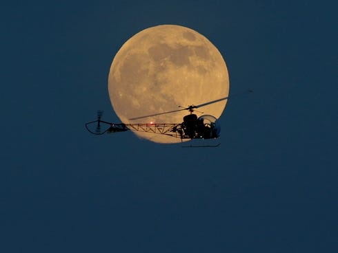 The moon is seen in its waxing gibbous stage as it rises behind the helicopter from the original Batman television show, which people can ride the New Jersey State Fair, Saturday.