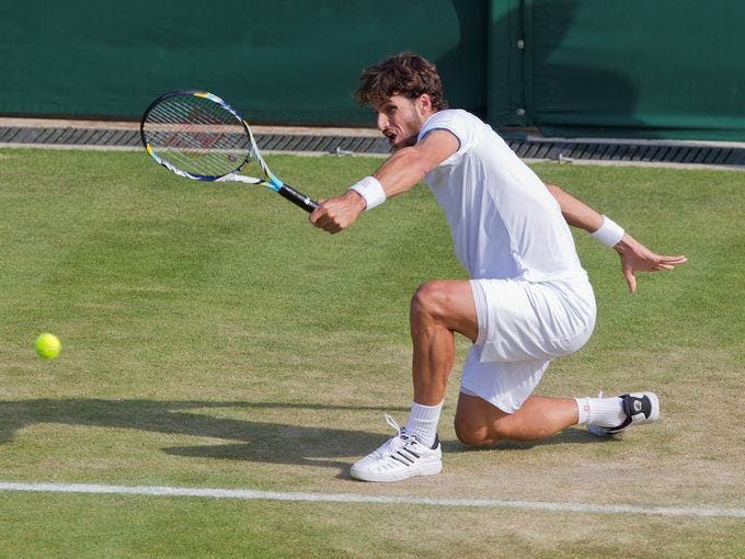 Feliciano Lopez hits from his knees and returns a backhand shot to Tommy Haas.
