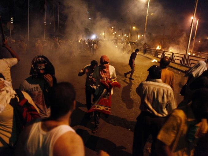 People run for cover as security forces fire tear gas to disperse supporters of ousted Egyptian president Mohammed Morsi outside the Republican Guard headquarters in Cairo in the early hours of July 8.
