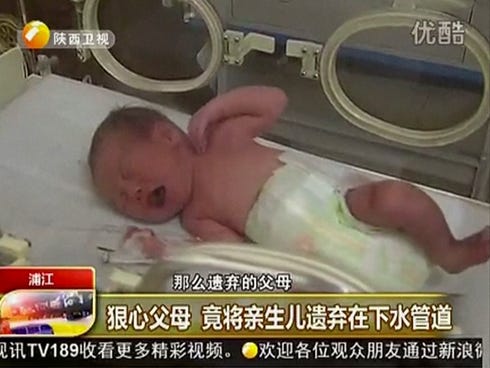 In this still image made from video from May 25, 2013, a baby who was rescued after being trapped in a sewage pipe just below a squat toilet in a public building, lies on a bed at a hospital in Jinhua city, eastern China.