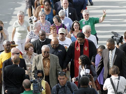 The Rev. William Barber, right center, with red sash, leads a group into the Legislative Building as the Monday protests are held at the General Assembly in Raleigh, N.C.