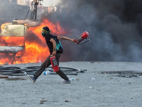 A man runs carrying fire extinguishers past a burning van during clashes at the Taksim Square in Istanbul.