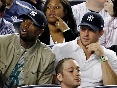ORG XMIT: NYY107 Miami Heat's Dwayne Wade, left, sits beside New York Jets quarterback Tim Tebow during the New York Yankees baseball game against the Los Angeles Angels at Yankee Stadium in New York, Sunday, April 15, 2012. (AP Photo/Kathy Willens)