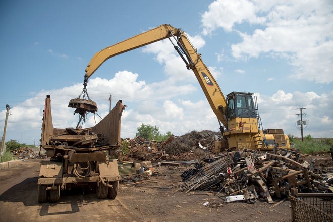 在金梅尔废铁厂，工人们将废金属放入一辆卡车 & 金属有限公司. 8月11日，底特律的废料场. 8, 2018.
