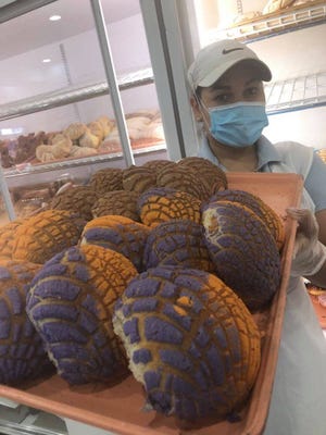A staff member at La Purisima Bakery in Glendale holds a tray of Suns conchas. The owners are big Suns fans and began making the sweet bread using the team colors to show their support.