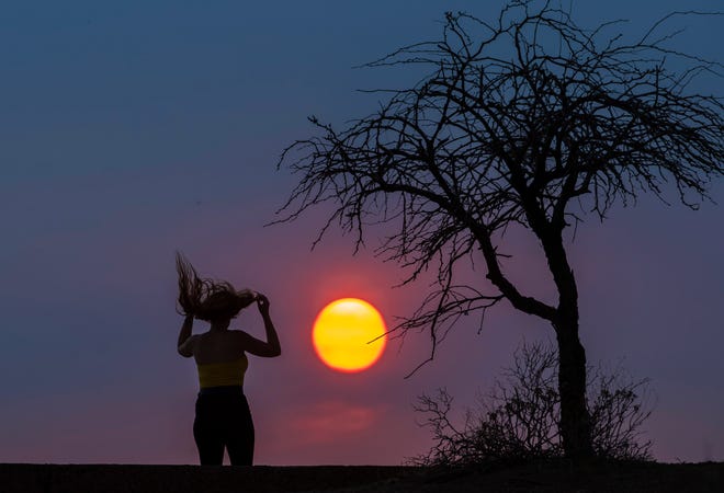 Danielle Fox runs her fingers through her hair while hiking at Papago Park as the sun sets in Phoenix on June 14, 2021. The National Weather Service in Phoenix issued an excessive heat warning for portions of south-central Arizona through the week.