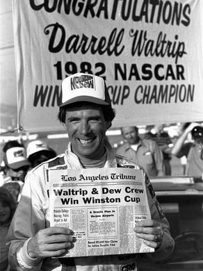 NASCAR driver Darrell Waltrip holds a fake newspaper