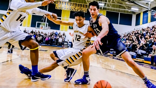 Josh Horford ,12, of Grand Ledge pushes Brandon Johns ,right, of East Lansing away from a loose ball under the Grand Ledge basket for a foul late in the 4th quarter.