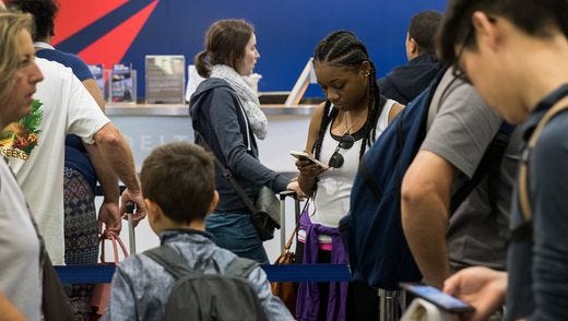 Travelers wait in line at the Delta check-in counter at New York LaGuardia.